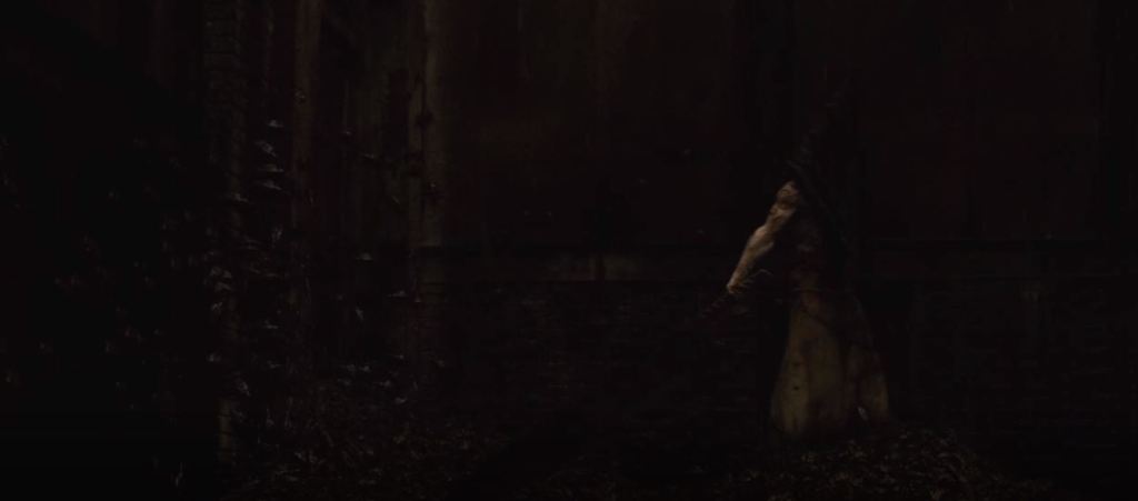 A hoard pf cockroaches are seen on the walls and ground. Walking through them is a giant figure of a large, muscular humanoid man with a giant sword and a metal pyramid shaped object covering his entire head.