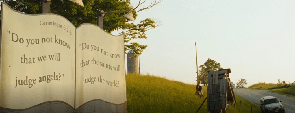 A billboard on the side of a sunny highway quotes a Biblical verse from Corinthians 6:2-3 stating "Do you not know that we will judge the angels? Do you not know that the saints will judge the world?"